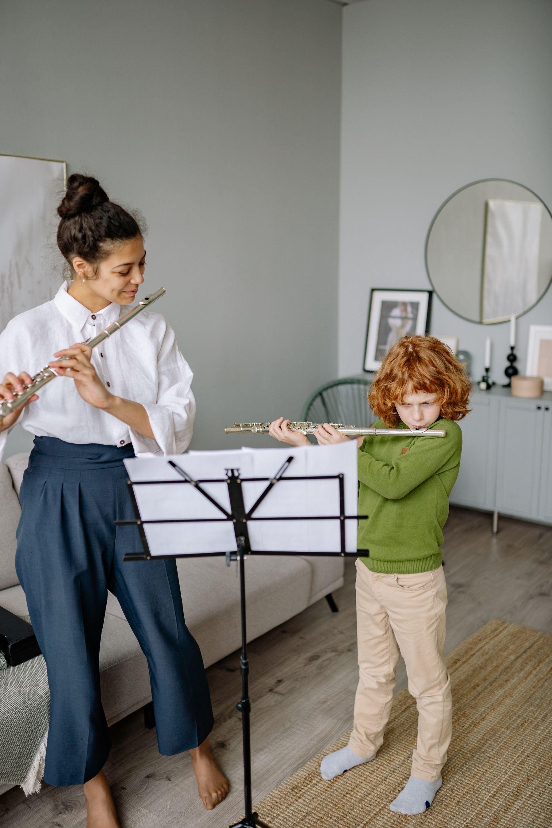 A child learning to play the flute with a teacher at home.